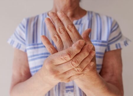 Idosa com doença de Parkinson segurando sua mão